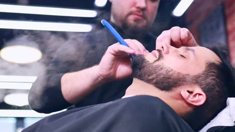 Hispanic bearded man having his hair cut by hairdresser at the barbershop Stock Footage 155547960