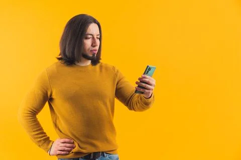 A hispanic bearded man thinking and looking into a cellphone, reading a message Stock Photos
