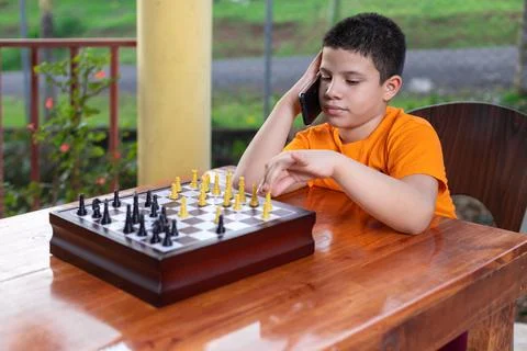 Hispanic boy calling on the phone while playing chess Stock Photos