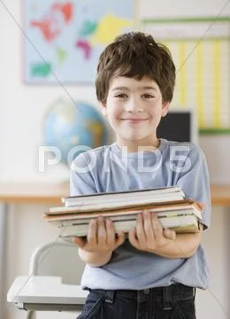 Hispanic boy holding stack of school books Stock Photos