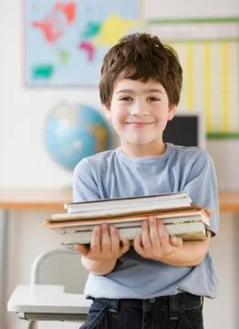 Hispanic boy holding stack of school books 스톡 사진