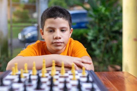 Hispanic boy looking at the chess board to make his move Stock Photos