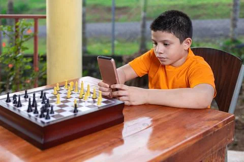 Hispanic boy looking at his cell phone while watching the game Stock Photos