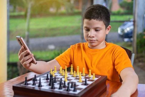 Hispanic boy looking at his cell phone while watching the game Stock Photos