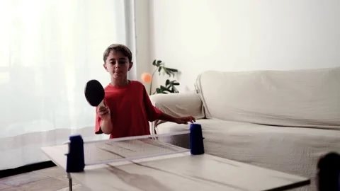 Hispanic boy playing ping pong with portable table tennis set at home. Family Stock Footage 323336525