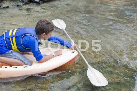 Hispanic boy reaching for oar in water Stock Photos