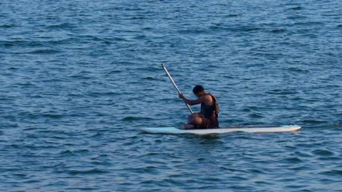 Hispanic boy sitting on surfing board and rowing on lago Paranoa Vídeo Stock 210471603