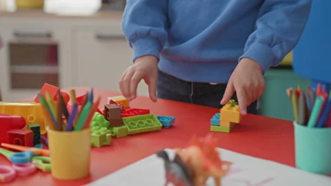 Hispanic boy stacking plastic building blocks with hands on red classroom t.. Stock Footage 339154801
