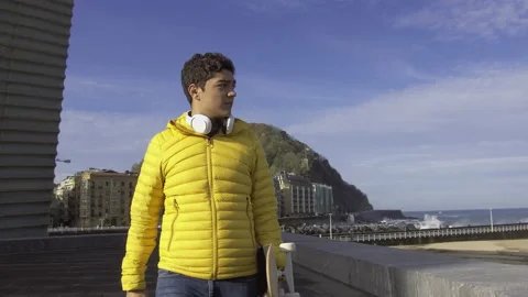 Hispanic boy walking while holding a skateboard Stock Footage 222575544