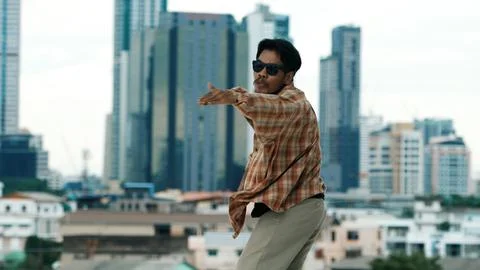 Hispanic break dancer practice B-boy footsteps at roof top with city. Endeavor. Stock Photos
