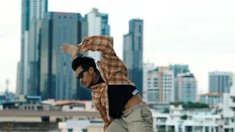 Hispanic break dancer practice B-boy footsteps at roof top with city. Endeavor. Stock Photos