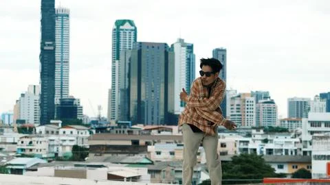 Hispanic break dancer practice B-boy footsteps at roof top with city. Endeavor. Foto stock