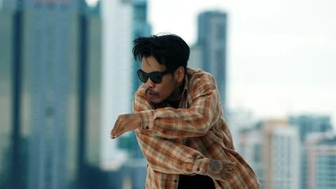 Hispanic break dancer practice B-boy footsteps at roof top with city. Hiphop. Stock Photos