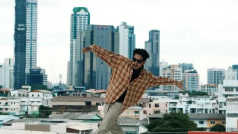Hispanic break dancer practice B-boy footsteps at roof top with city. Hiphop. Stock Photos