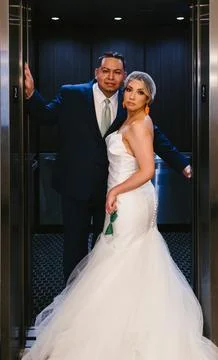 Hispanic bride and groom in elevator in suit and wedding gown Stock Photos
