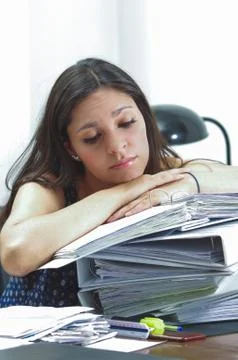 Hispanic brunette office worker sitting by desk and lying over pile of archive 스톡 사진