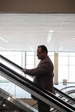 A hispanic businessman checking his notebook computer on an escalator Stock Photos