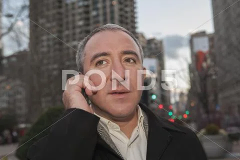 Hispanic businessman talking on cell phone on city street Stock Photos