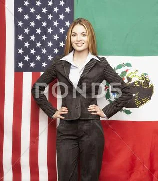 Hispanic businesswoman in front of American and Mexican flags Stock Photos