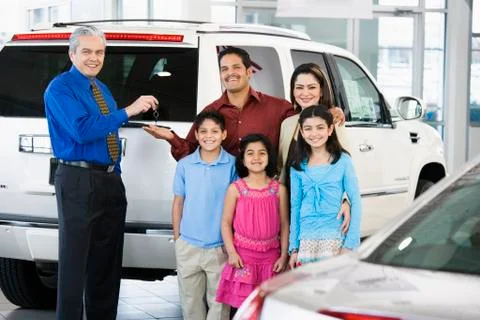 Hispanic car salesman handing car keys to family Stock Photos