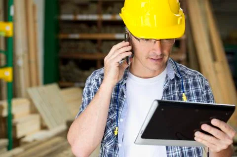 Hispanic carpenter using cell phone and digital tablet Stock Photos