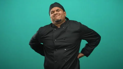 Hispanic chef man wearing black chef coat and headscarf holding lower back .. Stock Footage 339179139