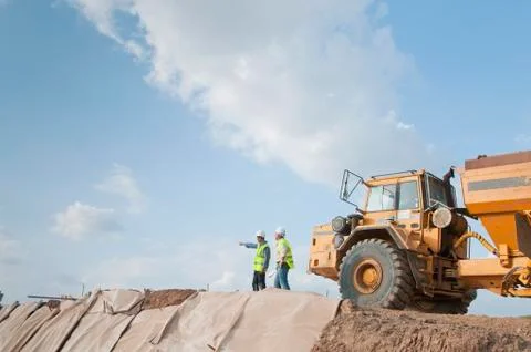 Hispanic construction workers in field with dump truck Stock Photos
