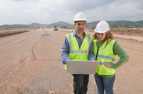 Hispanic construction workers using laptop in field Foto stock
