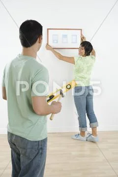 Hispanic couple hanging picture Stock Photos