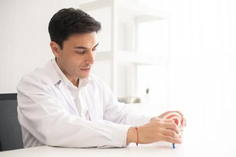 Hispanic dentist explaining to patient about teeth and how to brush with de.. Stock-Fotos