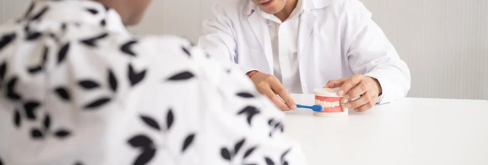 Hispanic dentist explaining to patient about teeth and how to brush with de.. Stock Photos