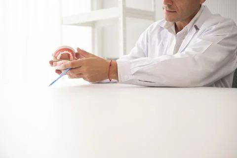 Hispanic dentist explaining to patient about teeth and how to brush with de.. Stock Photos