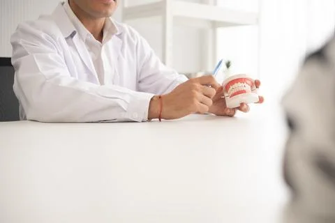 Hispanic dentist explaining to patient about teeth and how to brush with de.. Stock Photos