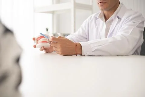 Hispanic dentist explaining to patient about teeth and how to brush with de.. Stock Photos
