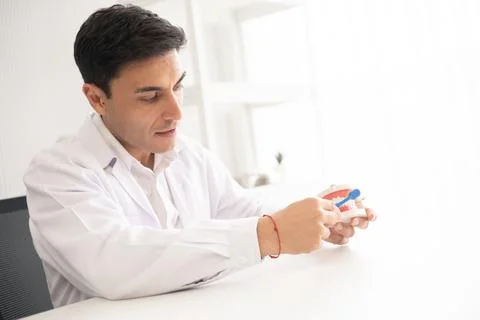 Hispanic dentist explaining to patient about teeth and how to brush with de.. Stock Photos