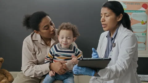 Hispanic Doctor Explaining Medical Data on Tablet to Biracial Mother with Child Stock Footage 339790444