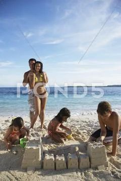 Hispanic family building sand castle Stock Photos