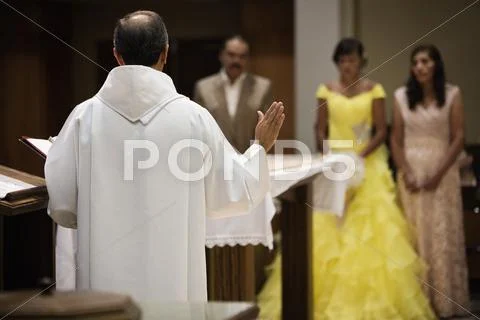 Hispanic Family Celebrating Quinceanera With Priest In Catholic Church
