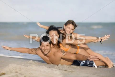 Hispanic family laying on beach Stock Photos