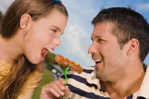 Hispanic father and daughter eating from same fork Stock Photos