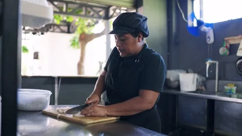 Hispanic female cook cutting raw meat in a commercial kitchen Stock Footage 330899158