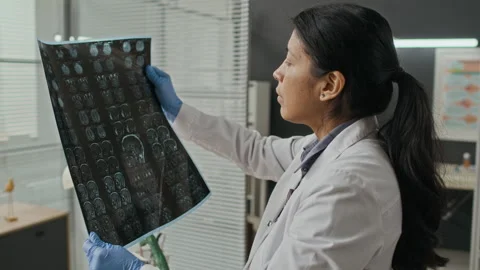 Hispanic Female Doctor Analyzing Brain Mri Scan Film in Clinic Stock Footage 339784848