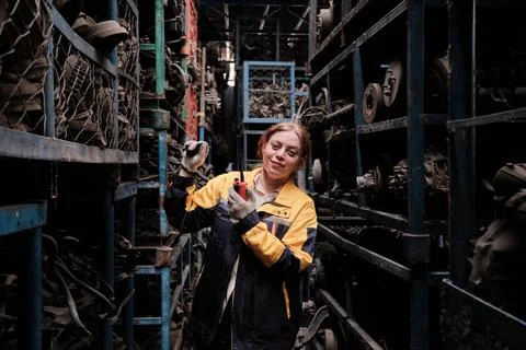 Hispanic female inspector checking auto parts stock in a warehouse stack. Stock Photos