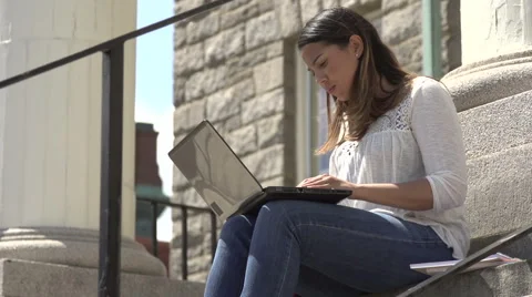 A hispanic female student types on laptop, on steps. Stock Footage 44117364