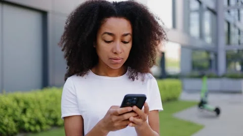 Hispanic female typing text on smartphone touch screen while standing outdoors Stock-Footage 280373629
