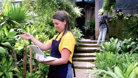 Hispanic gardening team using tablet at greenhouse during spring Stock Footage 329399516
