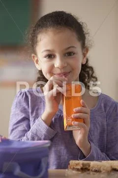 Hispanic girl drinking juice box for lunch at school Stock Photos