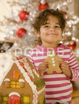 Hispanic girl next to gingerbread house Stock-Fotos