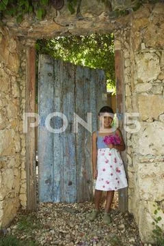 Hispanic girl standing in garden doorway Stock-Fotos
