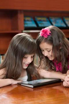 Hispanic girls using digital tablet in library 스톡 사진